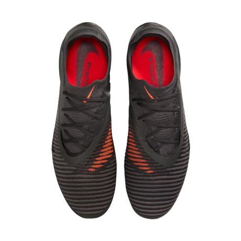 Top-down view of black and grey Nike Phantom soccer cleats featuring orange accents and insoles, set against a black background.