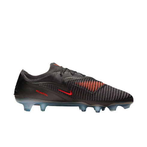 A side view of a dark grey Nike Phantom soccer cleat with red accents and translucent blue studs against a black background.