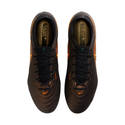 Top-down view of bronze Nike Tiempo Maestro soccer cleats with black laces and orange swoosh logos, set against a solid black background.