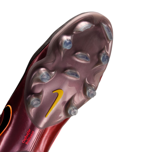 Underside of a metallic maroon Nike soccer cleat showing a pearlescent soleplate with clear studs, a yellow swoosh, and "Crafted for Brilliance" text.