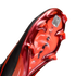 Bottom of a red and black soccer cleat with studs and "AIR ZOOM" text. A warning sticker states the plate finish will wear off with use.