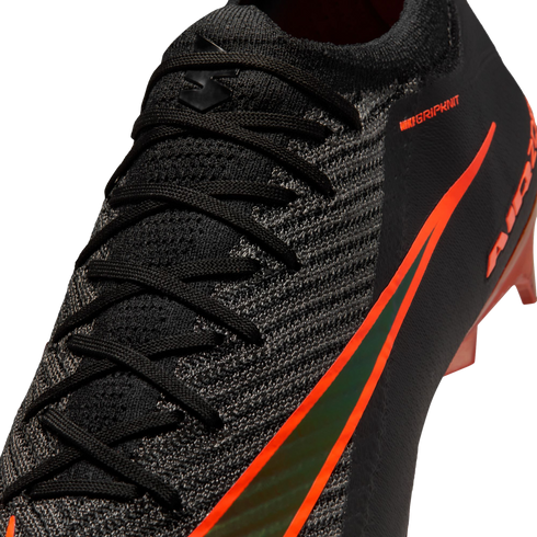 Close-up of a black Nike soccer boot featuring textured Gripknit, black laces, and a vibrant orange swoosh with an iridescent center.