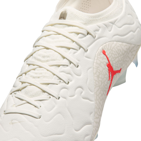 Close-up of a white Jordan Brand soccer cleat with a red Jumpman logo and grey elephant print pattern on the side.