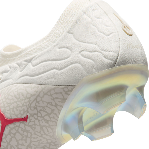 Close-up of a white Puma soccer cleat heel with a textured upper, a red Puma logo, and a semi-translucent iridescent soleplate with studs.