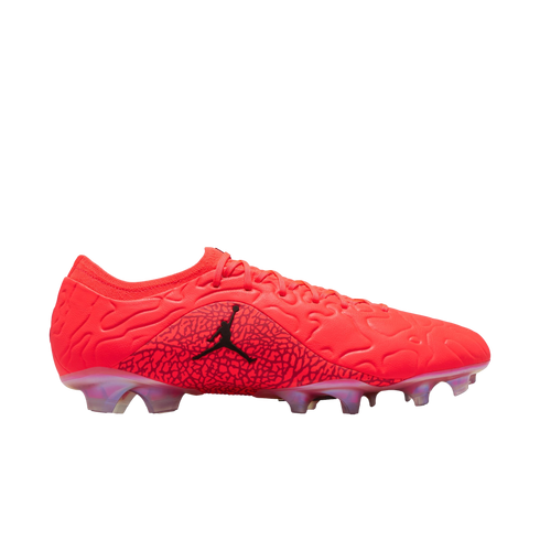 Side profile of a bright red Jordan soccer cleat with a textured upper, black Jumpman logo on an elephant print panel, and translucent studs, against a black background.