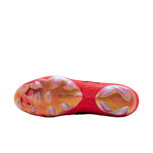 Bottom view of a red Nike Tiempo soccer cleat showing its iridescent soleplate, golden Nike swoosh, and stud pattern against a black background.