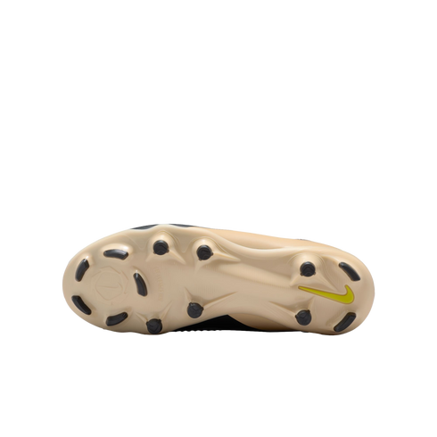 Underside of a beige Nike soccer cleat featuring black studs and a small neon green swoosh on the heel against a black background.