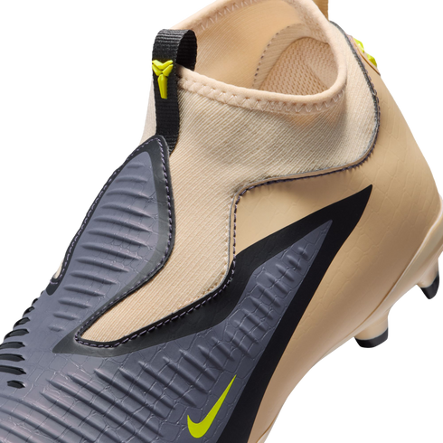 Close-up of a tan Nike soccer cleat featuring a textured grey striking zone, lime green swoosh, and a sock-like ankle collar.
