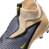Close-up of a tan Nike soccer cleat featuring a textured grey striking zone, lime green swoosh, and a sock-like ankle collar.
