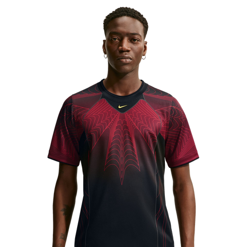 A man wearing a black Nike t-shirt with a large, red web-like graphic on the chest, facing forward against a white background.