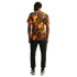 Back view of a man wearing a black t-shirt with a bold orange and yellow lion and chain pattern, black sweatpants, and silver sneakers.