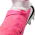 Close-up of a pink and white Nike soccer cleat featuring a textured upper and a high-top sock-like collar.