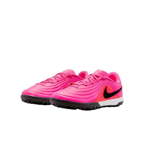 A pair of vibrant pink Nike turf soccer shoes with a black swoosh and textured upper, set against a plain white background.