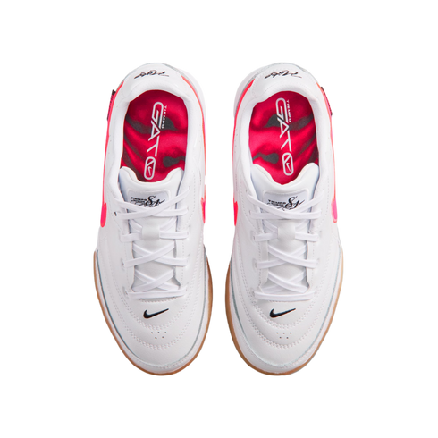 Top-down view of white Nike Tiempo Gato indoor soccer shoes with bright pink interiors, white laces, and gum outsoles.