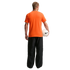 A rear view of a man standing against a black background, wearing a bright orange T-shirt and baggy black pants. He holds a white Nike soccer ball under his left arm.