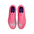 Top-down view of bright pink and silver Nike soccer cleats with matching pink laces and dark blue interiors, isolated on a black background.