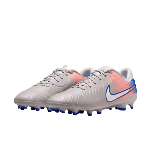 Light grey Nike soccer cleats with a pink and blue gradient heel, white swoosh, and blue studs on a black background.