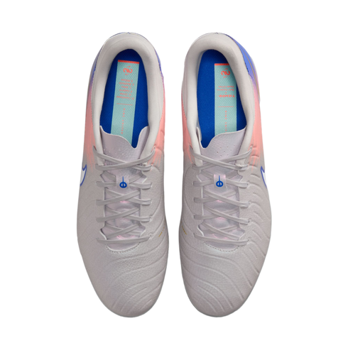 Top-down view of a pair of light grey Nike soccer cleats with pink and purple accents and blue insoles, centered against a solid black background.