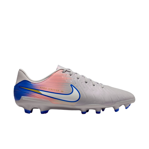 Side view of a light gray Nike soccer cleat with a pink and blue gradient heel, a white swoosh with blue trim, and blue studs, against a black background.
