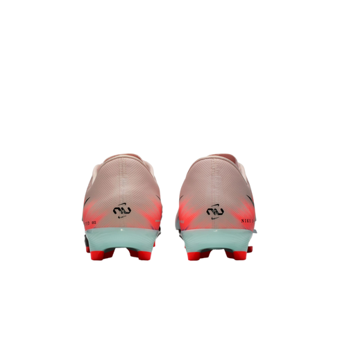 Rear view of pink and orange Nike soccer cleats with light blue heel counters and red studs against a black background.