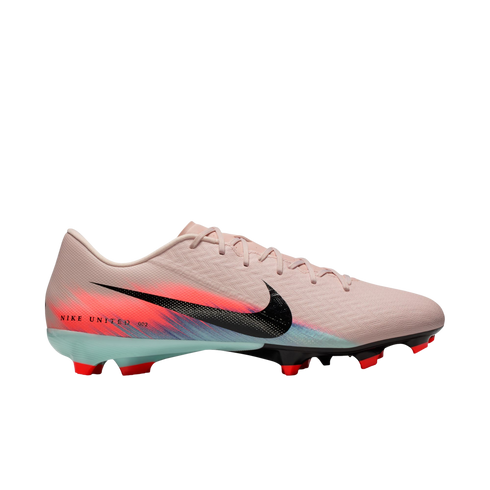 Side-view of a Nike soccer cleat in light pink with a black Swoosh and vibrant orange and blue graphic accents, set against a solid black background.