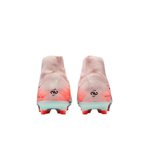 Rear view of two pink Nike soccer cleats with orange and black accents, featuring high-top ankle collars and bright orange studs.