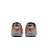 Rear view of a pair of orange and silver Nike athletic shoes with black accents on a white background.