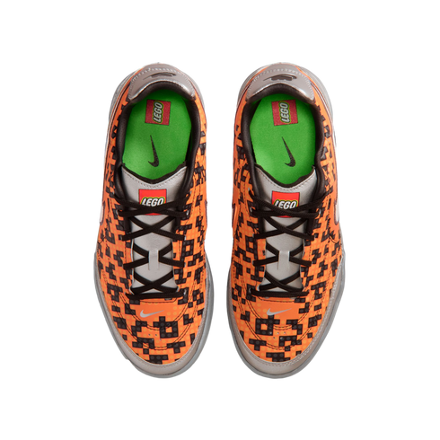 Top-down view of orange Nike sneakers with a black pixelated LEGO pattern, silver accents, and green insoles, featuring both Nike and LEGO branding.