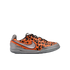 Side profile of an orange and black pixelated Nike indoor soccer shoe with metallic silver accents on a white background.