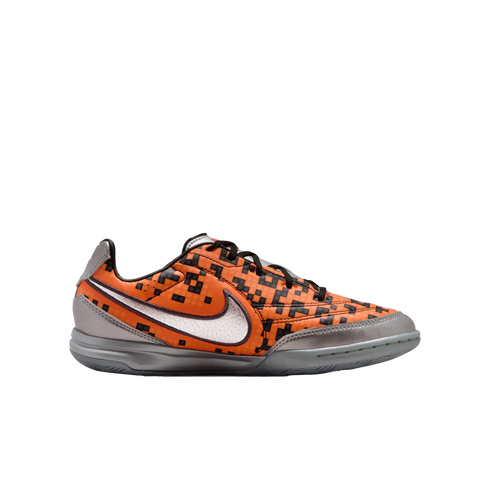 Nike indoor soccer shoe with an orange pixel-patterned upper, a silver swoosh, and metallic silver accents on the heel, toe, and sole.