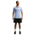 A man wearing a light blue Uruguay soccer jersey, black shorts, and white socks, standing against a black background.