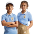 A boy and girl pose in light blue Uruguay national soccer team jerseys and Nike apparel against a black background.
