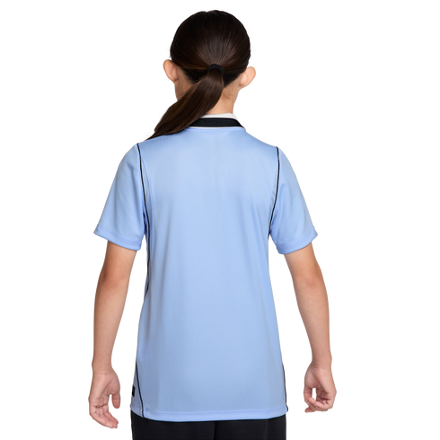 Back view of a person with dark hair in a ponytail wearing a light blue short-sleeved athletic shirt with black trim against a black background.
