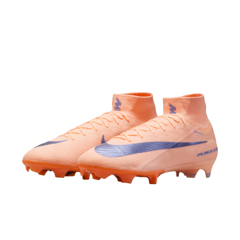 Peach-colored high-top Nike soccer cleats with a purple swoosh and orange studs, set against a black background.