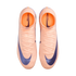 Top-down view of peach-colored Nike Mercurial soccer cleats with dark blue swooshes and high-top collars against a black background.