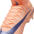 Close-up of a peach-colored Nike soccer cleat featuring a textured knit upper, matching laces, and a large purple swoosh.