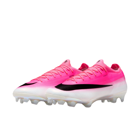 A pair of pink and white Nike soccer cleats featuring a large black swoosh and clear studs, shown against a plain white background.