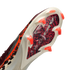 An angled, close-up view of the soleplate of a white soccer cleat, featuring a red and black leopard print pattern under a clear section with silver "AIR ZOOM" branding. The cleat has bright orange, translucent, chevron-shaped studs.