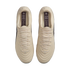 Top-down view of a pair of cream-colored Nike Tiempo soccer cleats with matching laces, displayed against a solid black background.