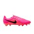 A side profile of a bright pink and red Nike soccer cleat with a black swoosh and textured upper against a white background.
