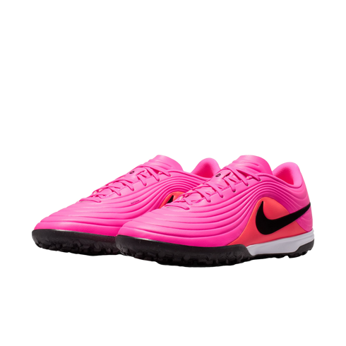 A pair of bright pink Nike turf soccer shoes featuring a textured upper, a black swoosh logo, and a black rubber outsole with traction nubs.
