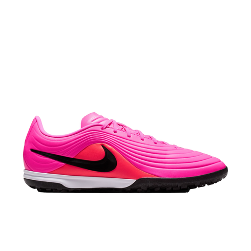 A side view of a bright pink Nike turf soccer shoe featuring a black swoosh, textured wavy upper, white midsole, and a black studded rubber outsole.