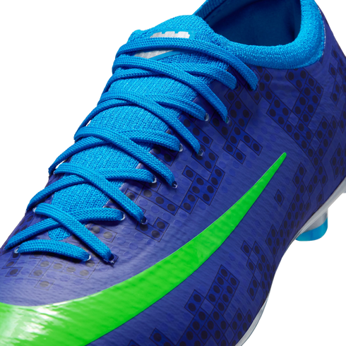 Close-up of a blue Nike soccer cleat with light blue laces, a bright green swoosh, and a dark blue LEGO brick pattern on the upper.