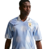 A man in a light blue Nike Uruguay football jersey with a white sun pattern and polo collar, looking to the side against a white background.