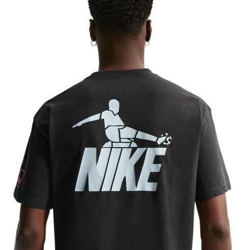 Rear view of a person wearing a dark t-shirt with a large light blue graphic of a stylized soccer player kicking a ball above the word "NIKE."