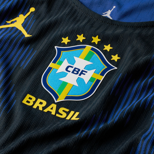 Close-up of a blue and black striped Brazil football jersey featuring the CBF crest, five gold stars, yellow "BRASIL" text, and a yellow Jordan Jumpman logo.