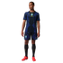 A man wearing a blue and black Brazil soccer kit with yellow Jordan logos and red cleats against a black background.