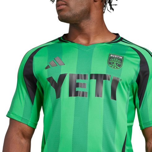 A person wearing a green and black striped Austin FC soccer jersey with the "YETI" logo on the front.