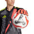 Goalkeeper in a black, red, and yellow jersey holding an Adidas Tiro Pro soccer ball with an orange-gloved hand against a green background.