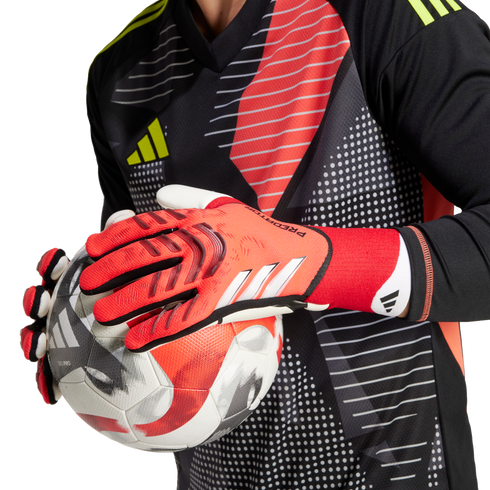 Goalkeeper in a patterned jersey and red Adidas gloves holding a soccer ball.